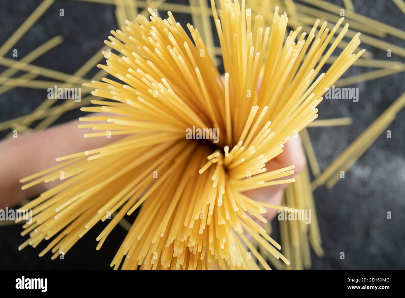 Frau Hände halten Spaghetti auf dunklem Hintergrund Stockfoto