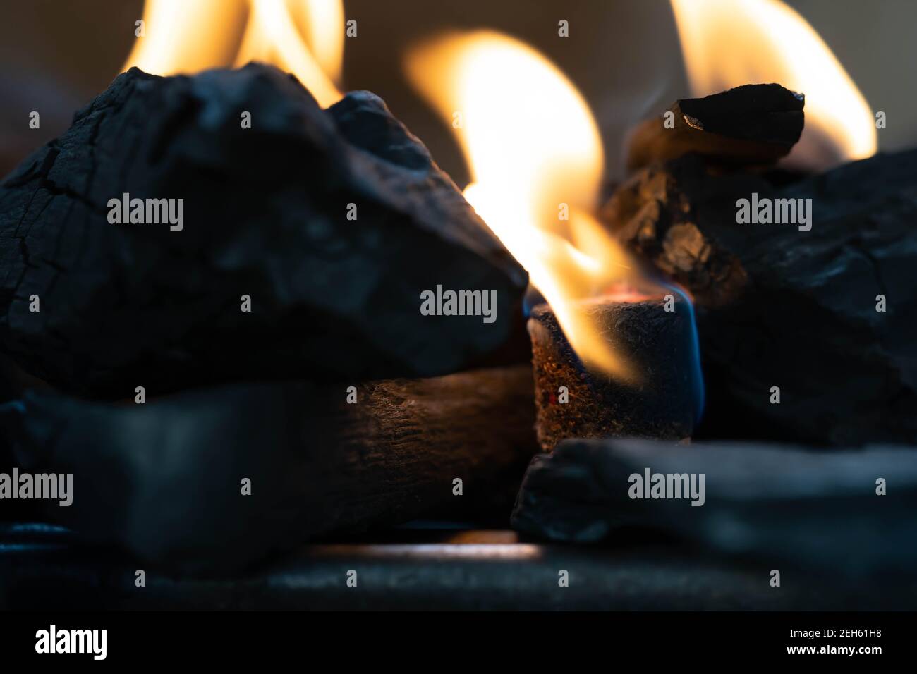 Glühende Grill Holzkohle Briketts in einem BBQ Kohle Feuerzeug. Feuerflamme wird mit Feuerstartern unter Holzkohle in der Grillkohle g platziert gestartet Stockfoto