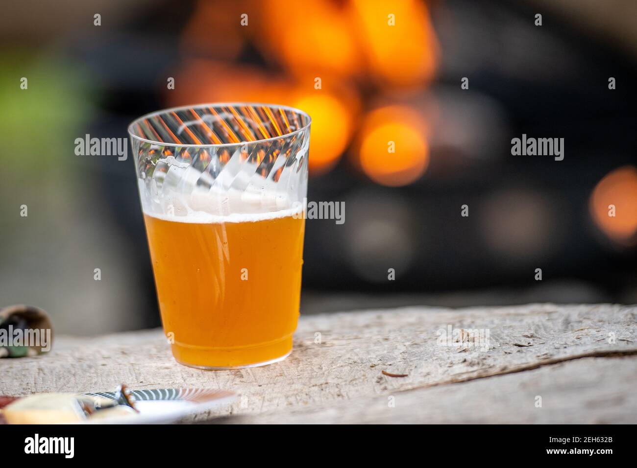 Schaumiges Bier auf einer Holzbank vor der Feuerstelle in Conowingo, Maryland Stockfoto