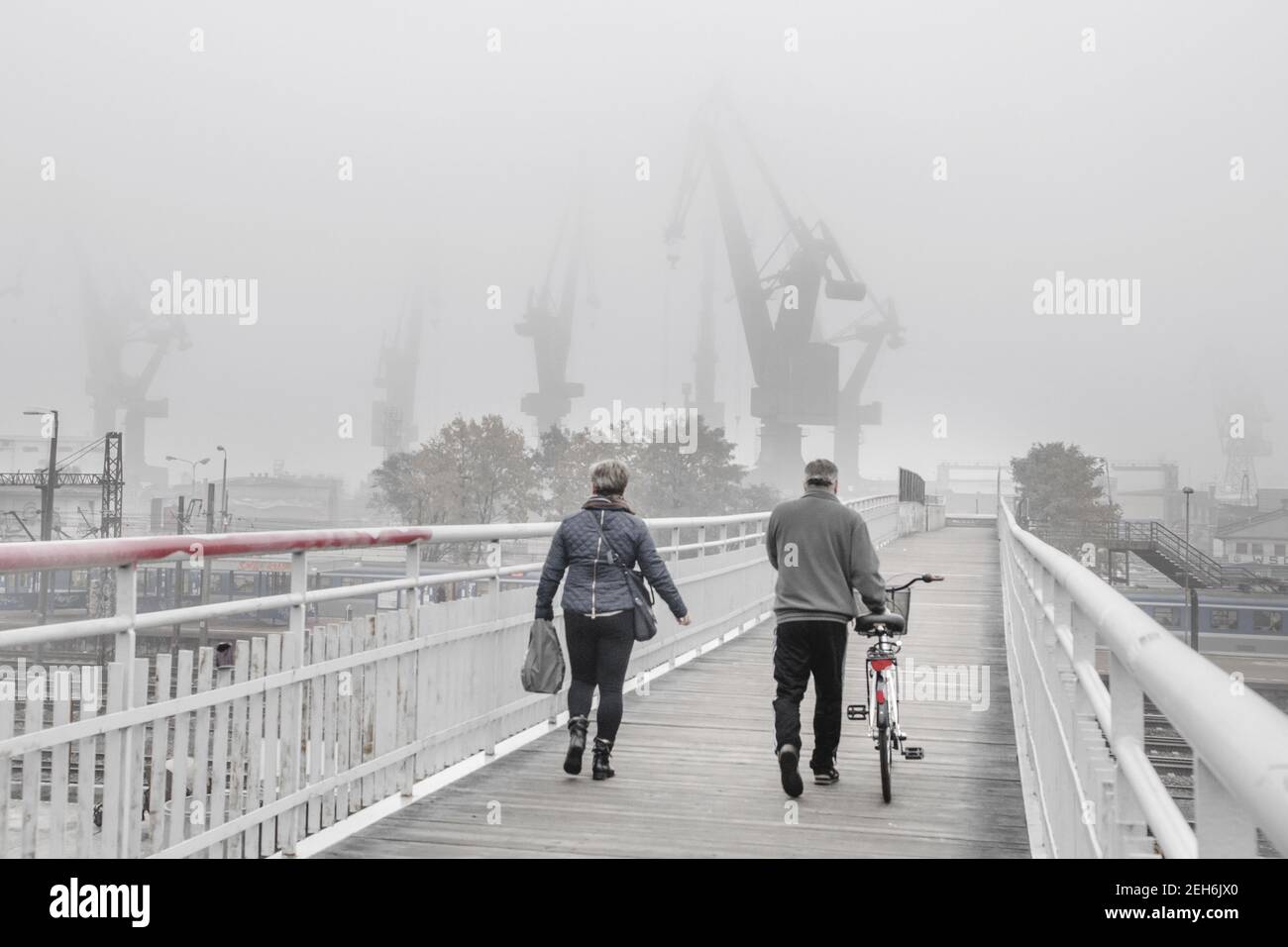 Blick auf zwei-Personen-Spaziergang auf der Fußgängerbrücke in der Werft in Danzig, Polen gegen einen nebligen Tag Stockfoto