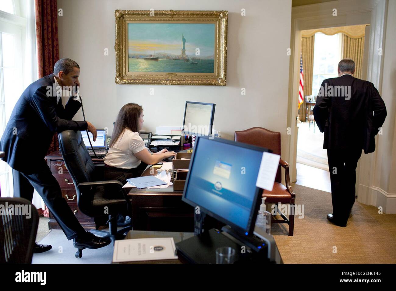 Präsident Barack Obama telefoniert mit einem Kongressabgeordneten, während Katie Johnson, die persönliche Sekretärin des Präsidenten, am 21. März 2010 an ihrem Schreibtisch im Outer Oval Office arbeitet. Phil Schiliro, Assistent des Präsidenten für Legislative Angelegenheiten, steht in der Nähe. Stockfoto