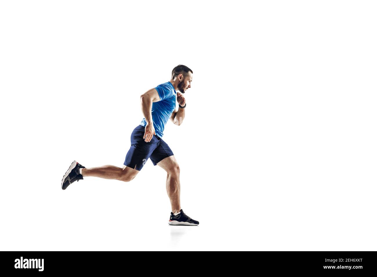 Zweck. Kaukasischer Profi-Athlet, Läufertraining isoliert auf weißem Studio Hintergrund. Muskulöser, sportlicher Mann. Konzept von Aktion, Bewegung, Jugend, gesunder Lebensstil. Copyspace für Werbung. Stockfoto