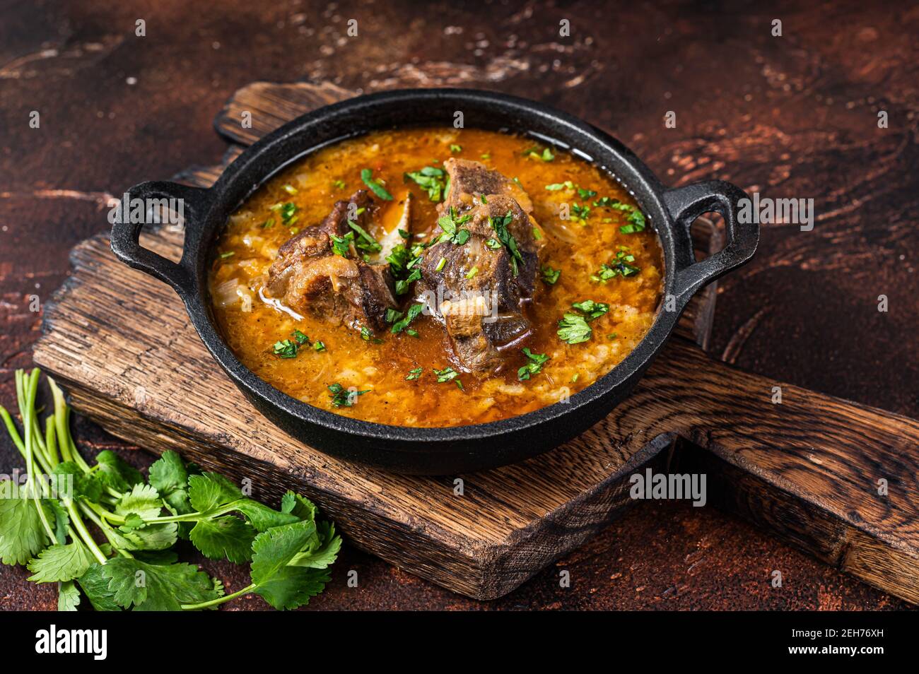 Kharcho Suppe mit Lammfleisch, Reis, Tomaten, Karotten, Paprika, Walnüsse und Gewürze. Dunkler Hintergrund. Draufsicht Stockfoto