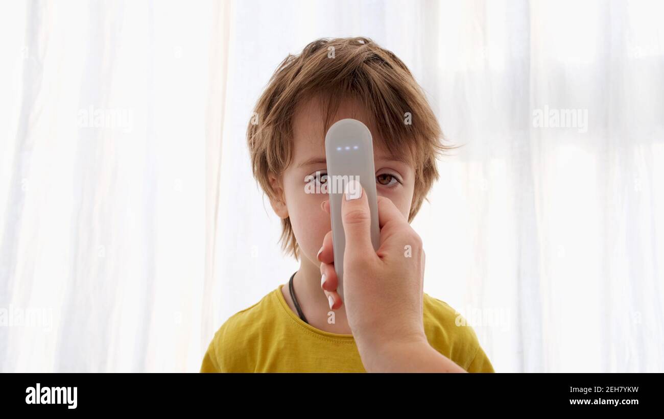 Nettes Kind hat Temperatur mit elektronischem Thermometer auf weiß gemessen Hintergrund Stockfoto