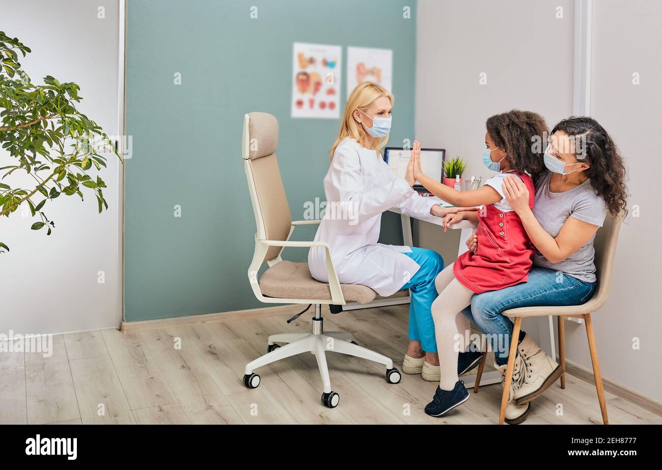 Afroamerikanisches Kind mit ihrer Mutter, die bei der Hausarztkonsultation Schutzmasken trägt. Besuch Arzt während einer globalen Pandemie Stockfoto