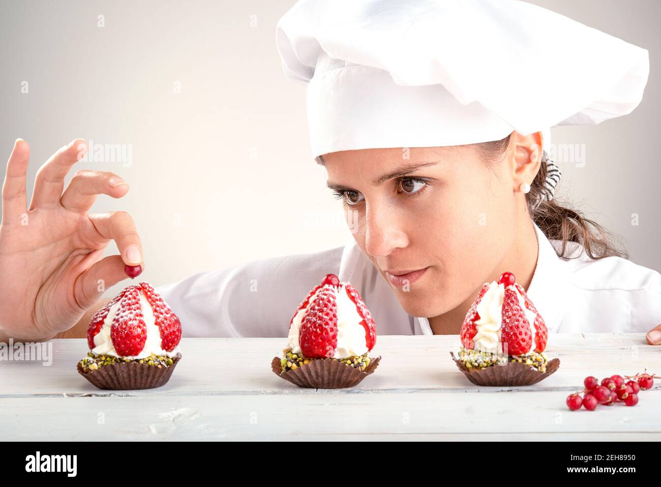 Chefin achtet auf die endgültige Dekoration der Erdbeere Cupcakes Stockfoto