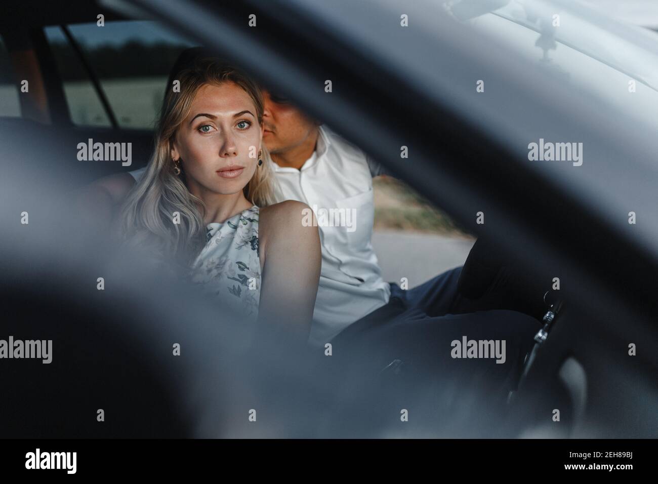 Mann wird Frau küssen, während er im Auto sitzt und Platz für Ihren Text hat. Glückliches Paar in einem Auto Stockfoto