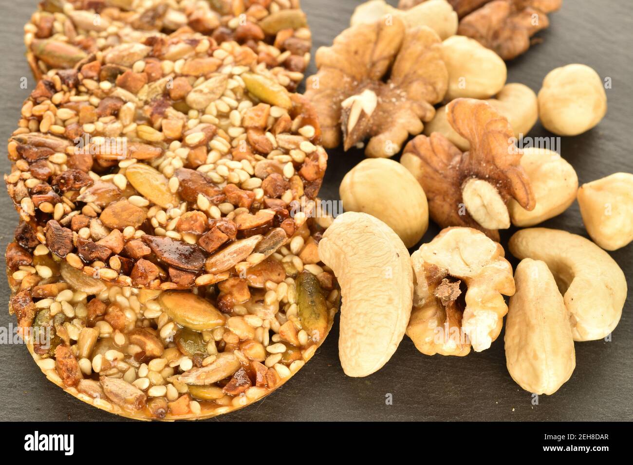 Mehrere ganze frische, duftende, köstliche nussige Kekse liegen zusammen mit natürlichen Nüssen, Nahaufnahme, auf einem Schiefertafel. Stockfoto