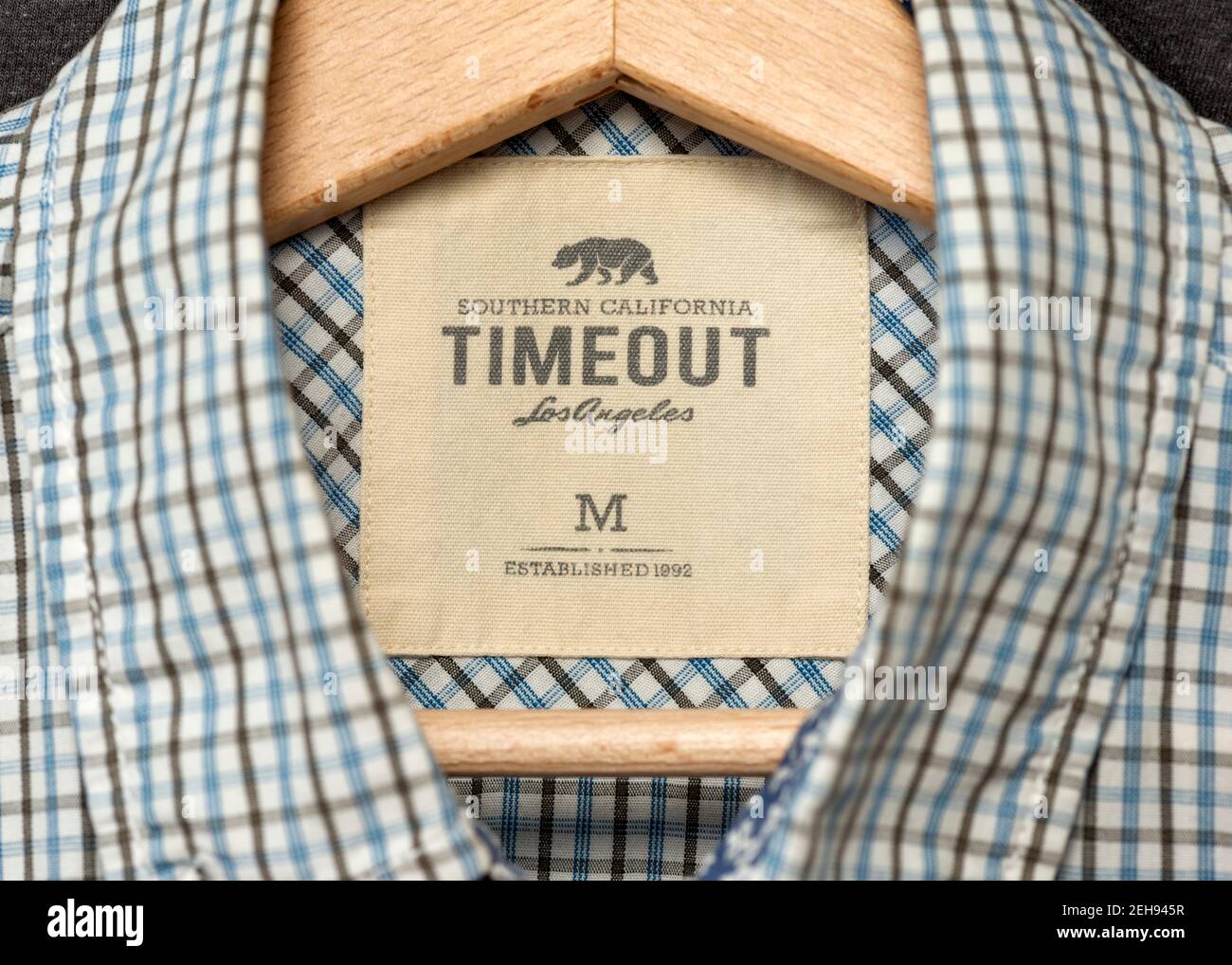Timeout Los Angeles Kleidung und Herrenmode Logo und Label auf Blaues Hemd, das auf einem Holzhänger hängt Stockfoto