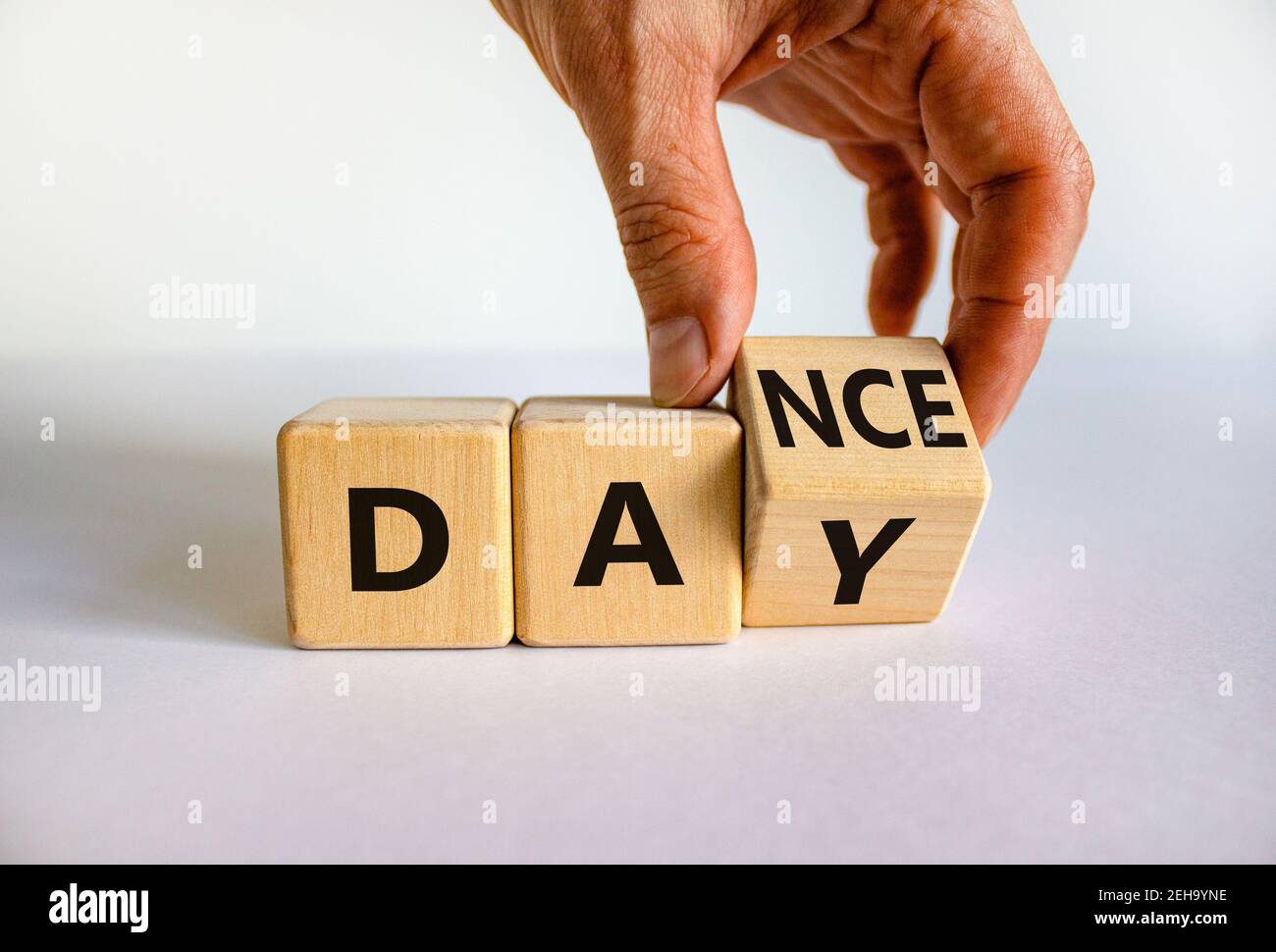 Symbol für den Internationalen Tanztag. Tänzer dreht Würfel mit den Worten 'Tanz Tag'. Schöner weißer Tisch, weißer Hintergrund, Kopierraum. Internationaler Tanz Da Stockfoto