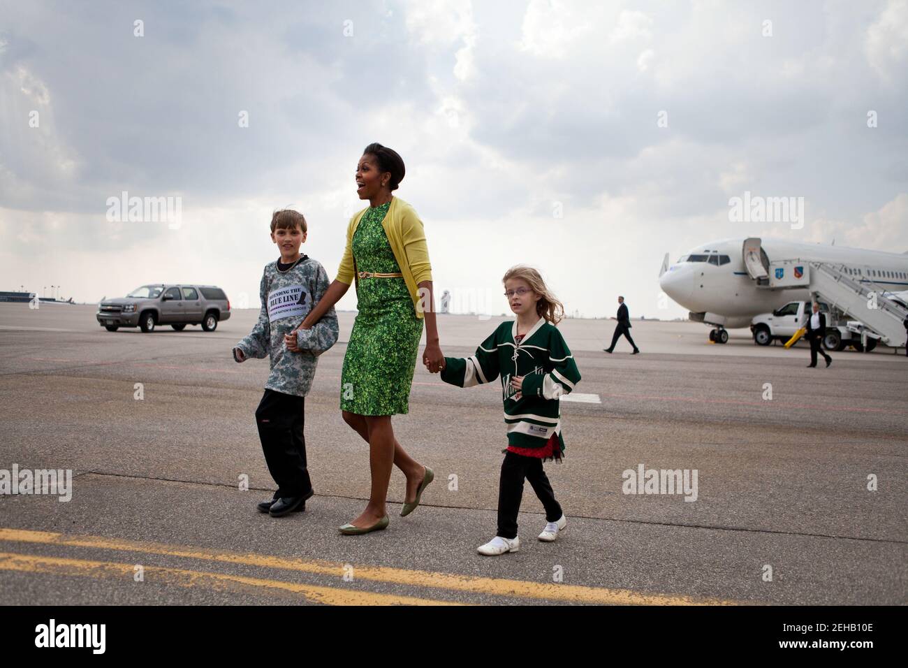 First Lady Michelle Obama geht mit Megan Soukup, 9, und Joseph Hudella, 10, Teilnehmern am Programm Defending the Blue Line, über den Asphalt, während sie sich darauf vorbereitet, Militärfamilien in Minneapolis-St. zu begrüßen Paul International Airport in Minneapolis, Minn., 16. März 2012. Die First Lady reiste nach Minnesota, um Familien der Nationalgarde und lokale Gemeindeführer zu treffen, die sich der Unterstützung von Militärfamilien verschrieben haben. Stockfoto