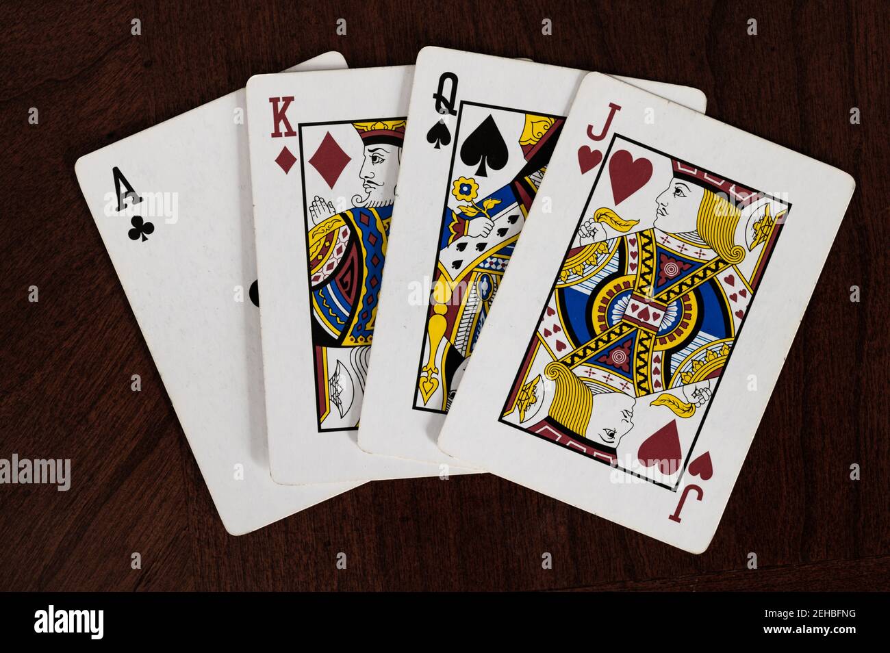 Ass der Keulen, König der Diamanten, Königin der Pik und Herz-Bube, die Karten auf dem Holztisch spielen Stockfoto