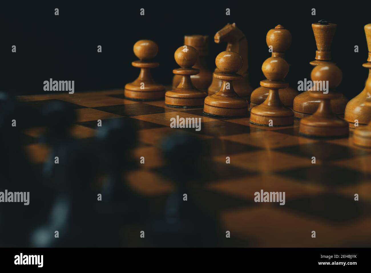Schwarze Schachfiguren gegen weiße Schachfiguren auf einem Schachbrett. Stockfoto