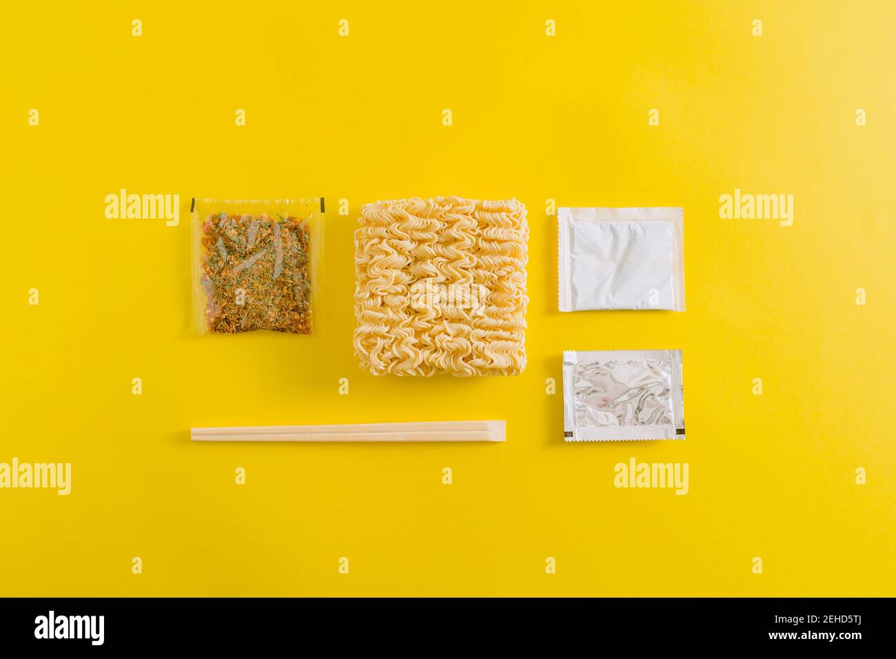 Draufsicht Layout von ungekochten Nudeln mit Gewürzen Zutaten und Klebt in Plastikverpackungen auf gelbem Hintergrund Stockfoto