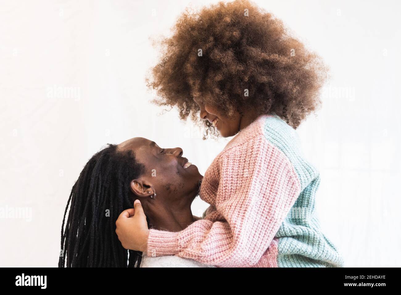 Seitenansicht des glücklichen afroamerikanischen Vaters umarmt Tochter während Hände tragen und einander anschauen Stockfoto