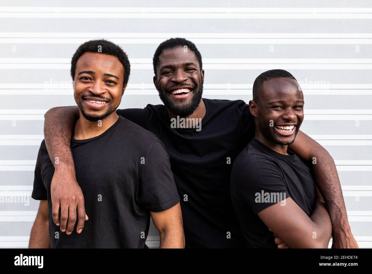 Inhalt beste afroamerikanische Freunde in schwarzen T-Shirts stehen Schließen, während Sie die Kamera auf hellem Hintergrund betrachten Stockfoto