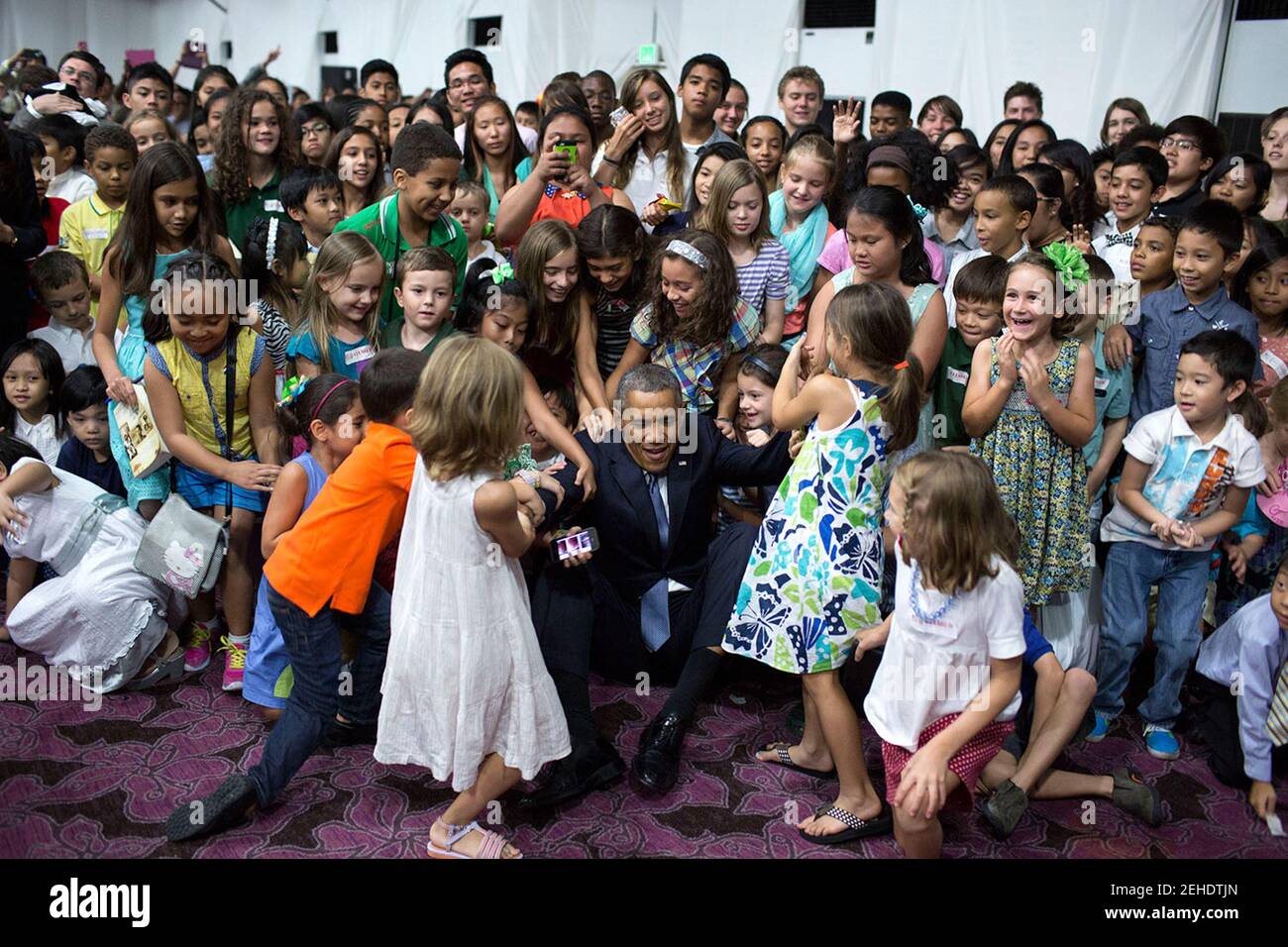 Kinder helfen Präsident Barack Obama auf den Beinen, nachdem er auf dem Boden saß, um ein Gruppenfoto mit ihnen zu machen, während eines US-Botschaftsmeet und Greet im Sofitel Philippine Plaza Manila in Manila, Philippinen, am 28. April 2014. Stockfoto