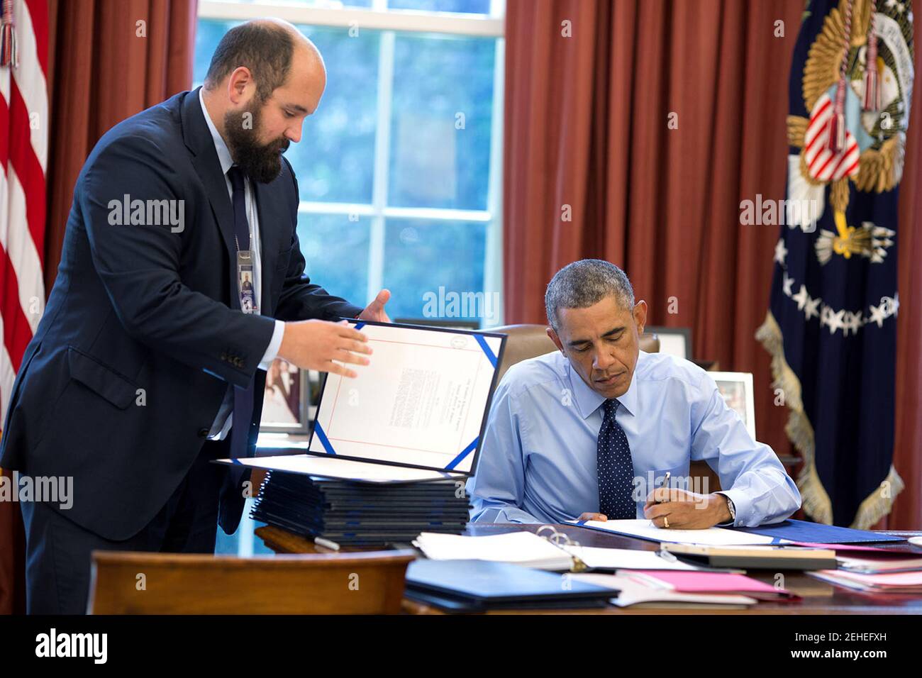 Präsident Barack Obama, unterstützt durch Personal Vizesekretär Ted Chiodo, unterschreibt Rechnungen im Oval Office, 26. September 2014. Stockfoto