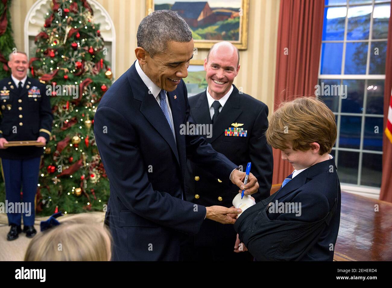Präsident Barack Obama unterzeichnet die Besetzung von Brayden Myers, 9, bei der Förderung-Zeremonie für Brayden Vater, Military Aide Lieutenant Commander Timothy J. "Tim" Meyers, USN, fördern ihn in den Rang eines Kommandanten im Oval Office, 5. Dezember 2014. Stockfoto