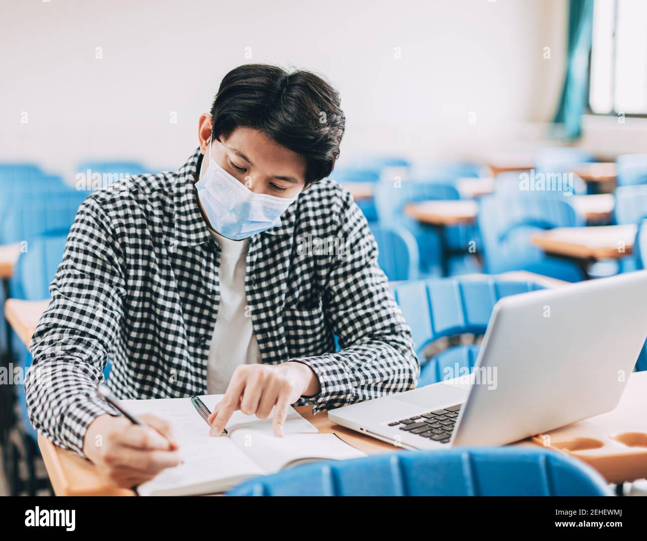 Junge Schüler tragen Gesichtsmaske und studieren im Klassenzimmer Stockfoto