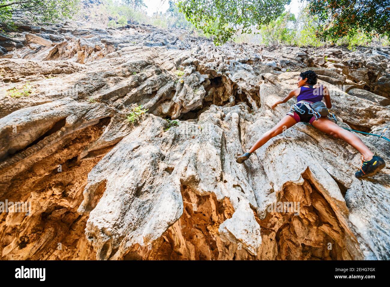 Frau klettert steile Kalksteinklippe in Laos Stockfoto