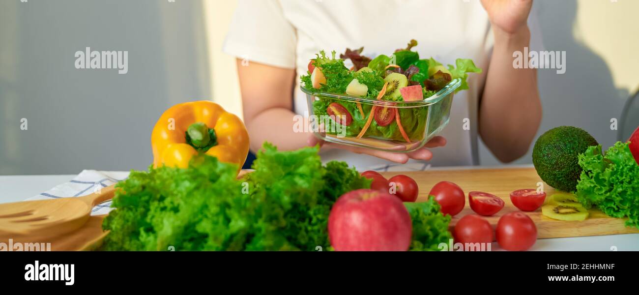 Nahaufnahme der Frau Hände zeigen Salatschüssel und verschiedene grüne Blattgemüse auf dem Tisch zu Hause. Stockfoto