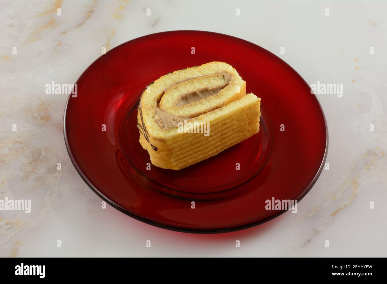Scheibe Tiramisu Kaffee Sahne Kuchenrolle auf rotem Glas Platte auf dem Tisch Stockfoto