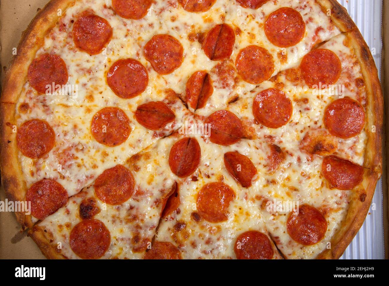 Draufsicht flache Lay von einer ganzen Pepperoni Pizza in Scheiben geschnitten in der Box. Stockfoto