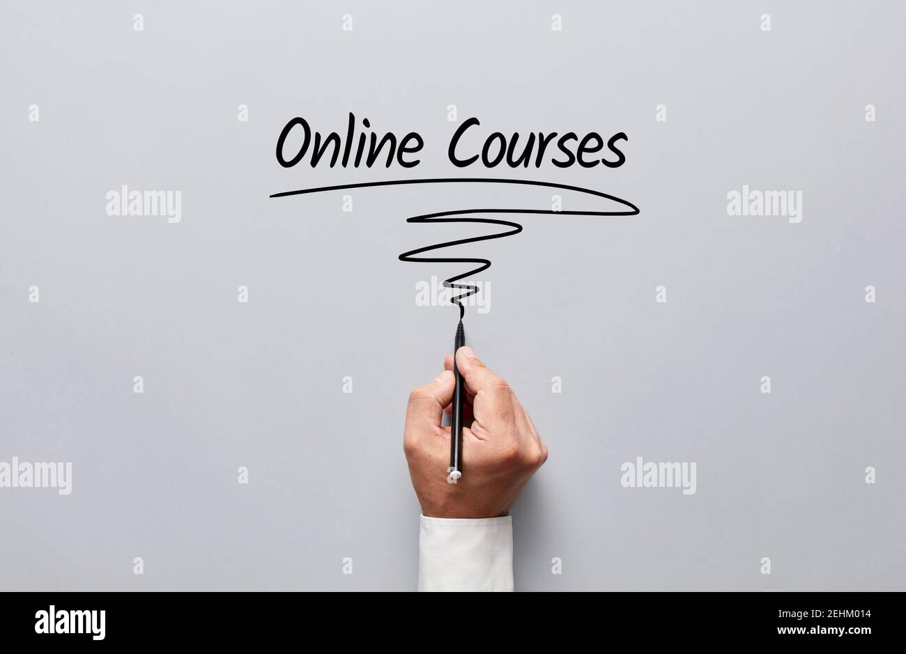 Männliche Hand schreiben Online-Kurse auf grauem Hintergrund. Online-Bildung und E-Learning-Konzept. Stockfoto