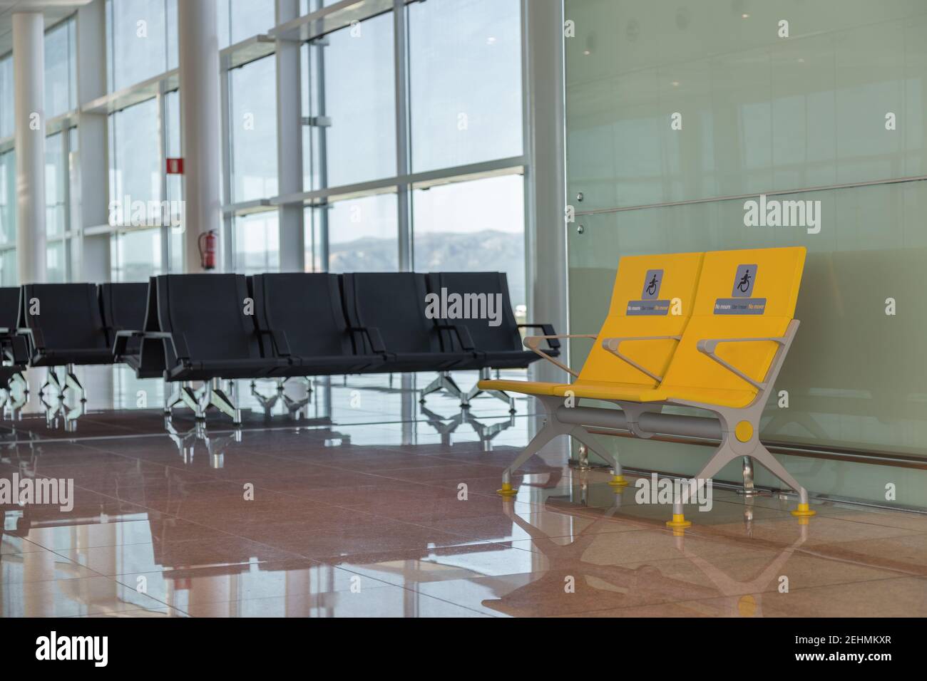 Leere Priority-Sitzplätze am internationalen Flughafen für Behinderte reserviert. Normale und gelbe Behindertensitze im Wartebereich vor dem Einsteigen. Stockfoto