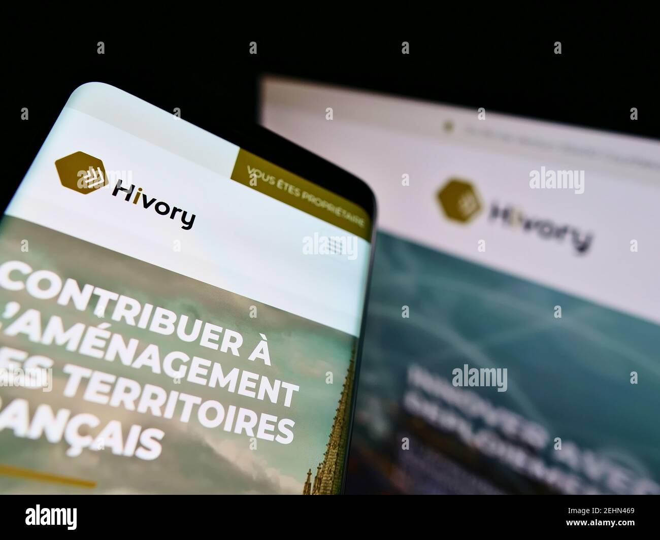 Mobiltelefon mit Business-Webseite des französischen Telekom-Tower-Unternehmens Hivory auf dem Bildschirm vor dem Monitor. Konzentrieren Sie sich auf die obere linke Seite des Telefondisplays. Stockfoto