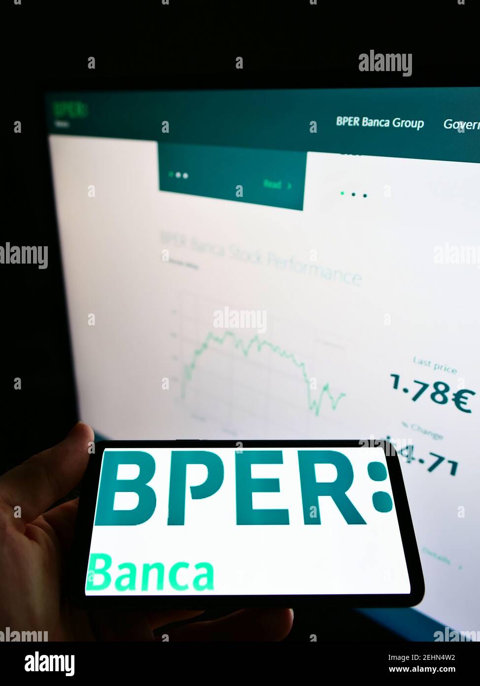 Person, die Mobiltelefon mit Logo der italienischen Bank BPER Banca S.p.A. auf dem Bildschirm vor der Website mit Aktienkurstabelle hält. Konzentrieren Sie sich auf die Telefonanzeige. Stockfoto