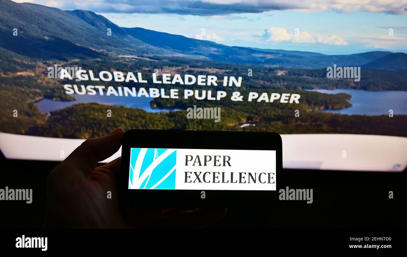 Person, die das Smartphone mit dem Logo des kanadischen Zellstoffherstellers Paper Excellence B.V. auf dem Bildschirm vor der Website hält. Konzentrieren Sie sich auf die Telefonanzeige. Stockfoto