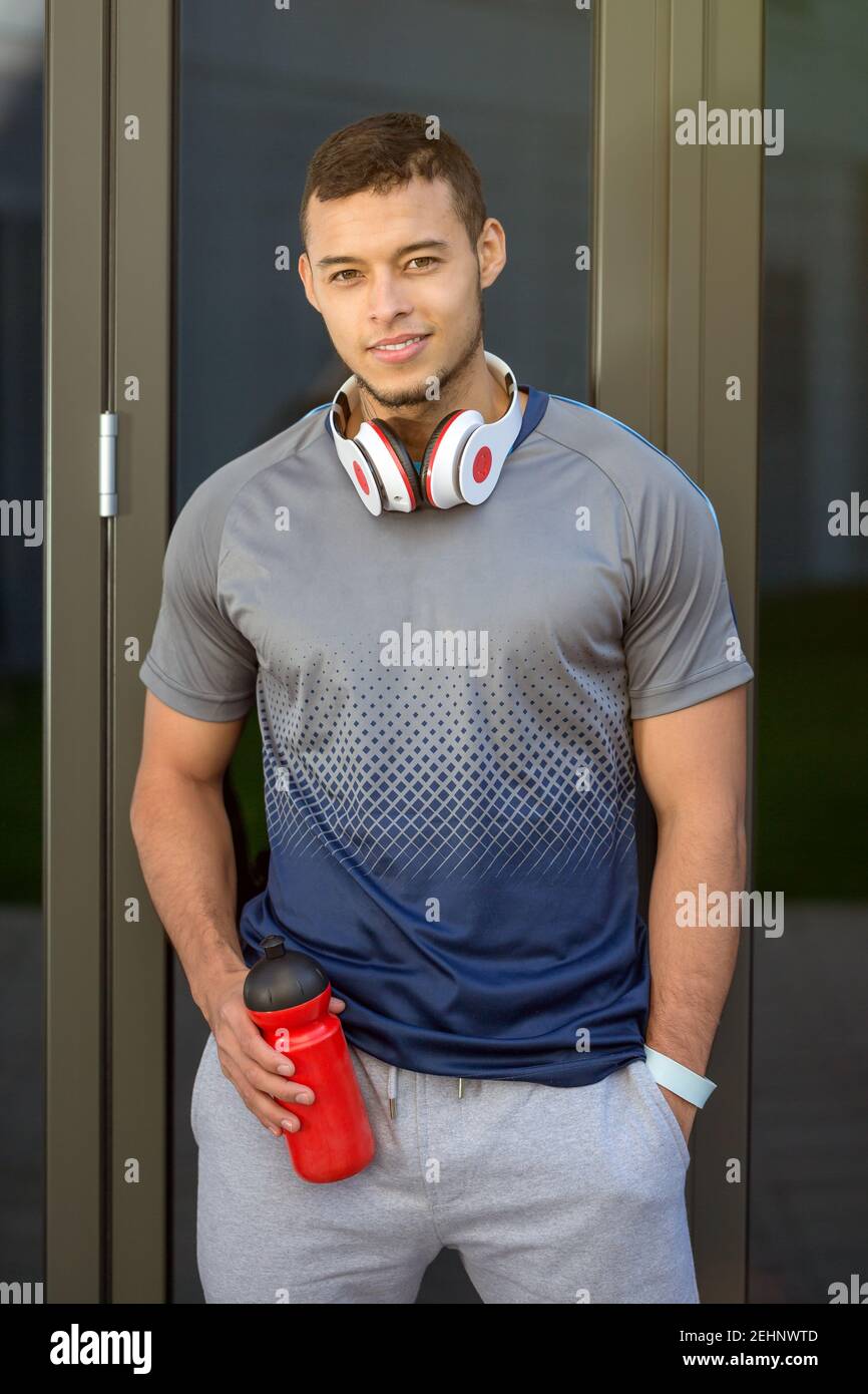 Lächelnd junge latein Mann Wasserflasche Läufer Porträt-Format Sport Fitnesstraining im Freien Stockfoto