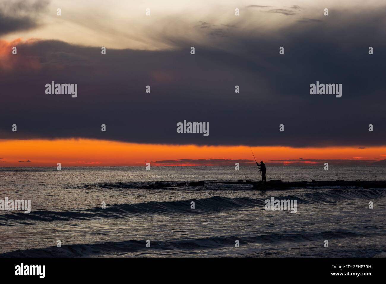 Fischer auf dem Meer bei Sonnenuntergang. Stockfoto