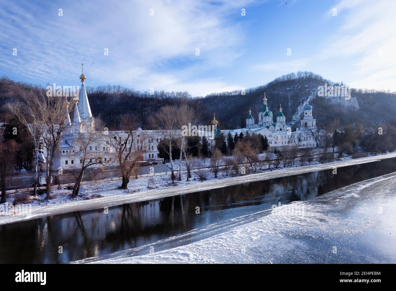 Kirche Swjatohirsk Lavra über dem Fluss Siwerski Donez im Winter. Es gibt kein Eis in der Mitte des Flusses, man kann eine verschwommene Reflexion sehen Stockfoto