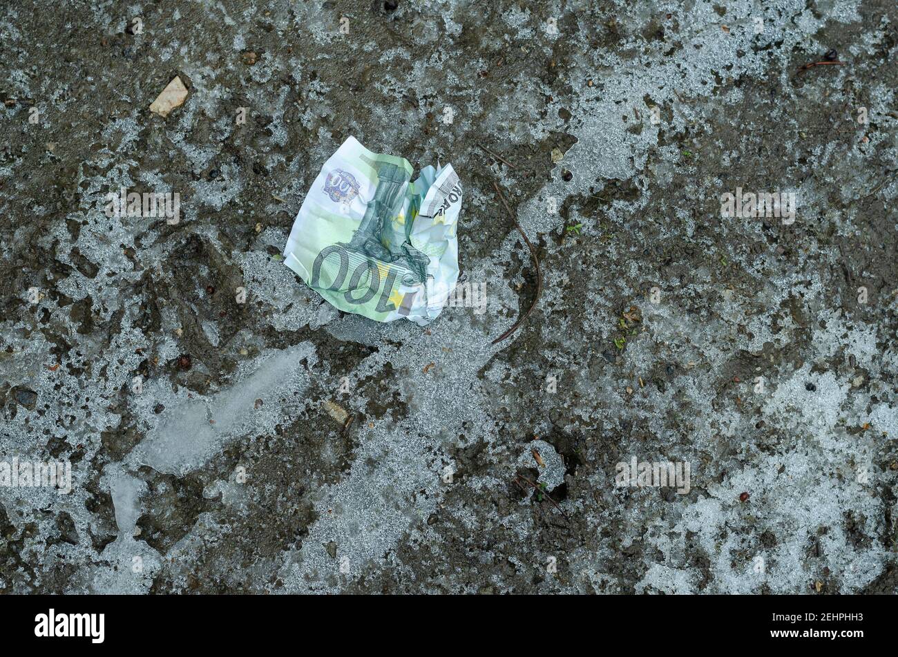 Ein zerknitterter ˆ 100-Schein liegt auf dem gefrorenen Boden. Geld verloren. Winter, im Freien. Keine Personen Stockfoto