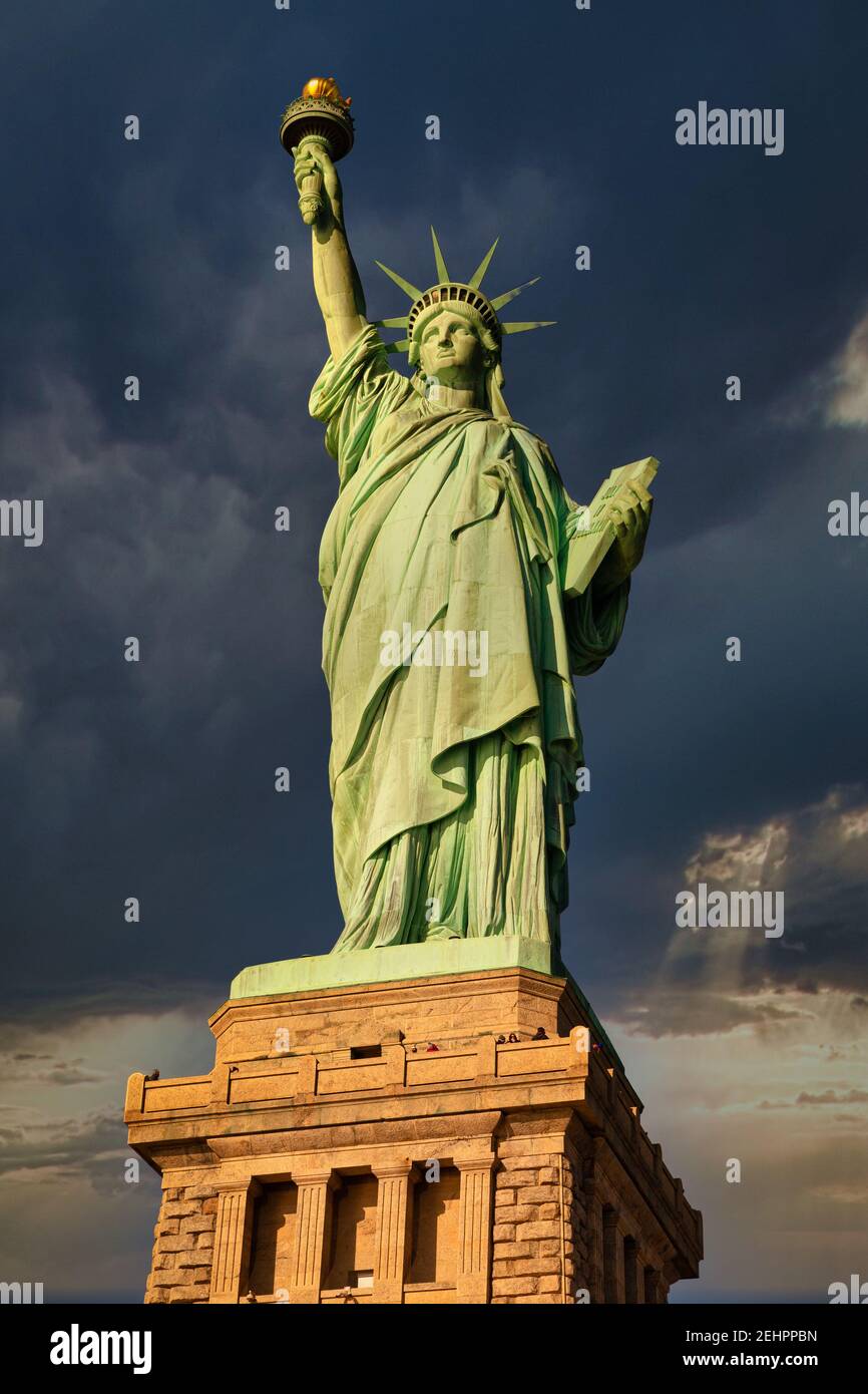 Die Freiheitsstatue in New York City USA Tageslicht Nahaufnahme aus tiefem Winkel mit Wolken am Himmel Im Hintergrund Stockfoto