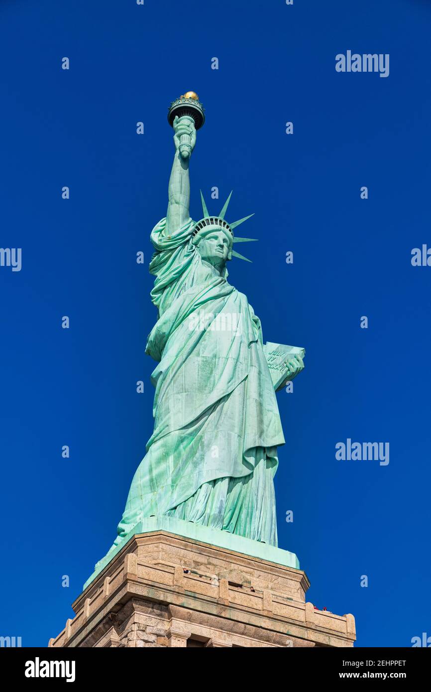 Die Freiheitsstatue in New York City USA Tageslicht Nahaufnahme aus tiefem Winkel mit blauem Himmel im Hintergrund Stockfoto