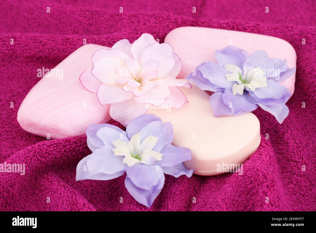 Bunte Seifen und Blumen auf rosa Handtuch. Stockfoto