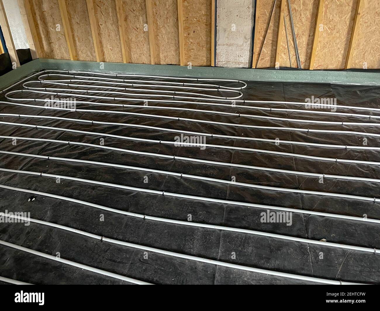 Fußbodenheizungsrohre auf schwarzen Kunststoffplatten auf dem Boden einer Gebäudeumrüstung in Rural Devon, England, Großbritannien verlegt Stockfoto