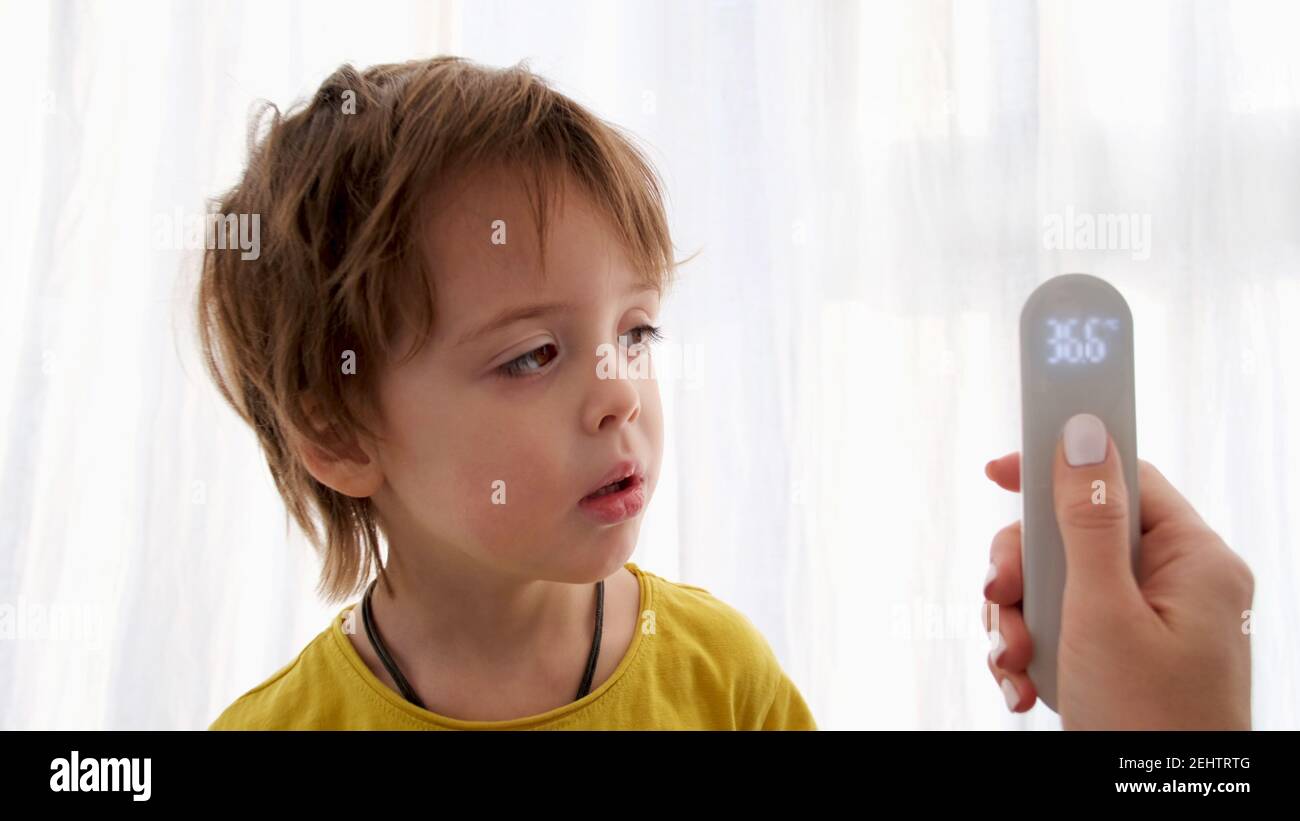 Nettes Kind hat Temperatur mit elektronischem Thermometer auf weiß gemessen Hintergrund Stockfoto