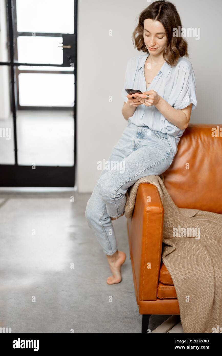 Frau mit Smartphone, während sie auf dem Sofa sitzt Stockfoto