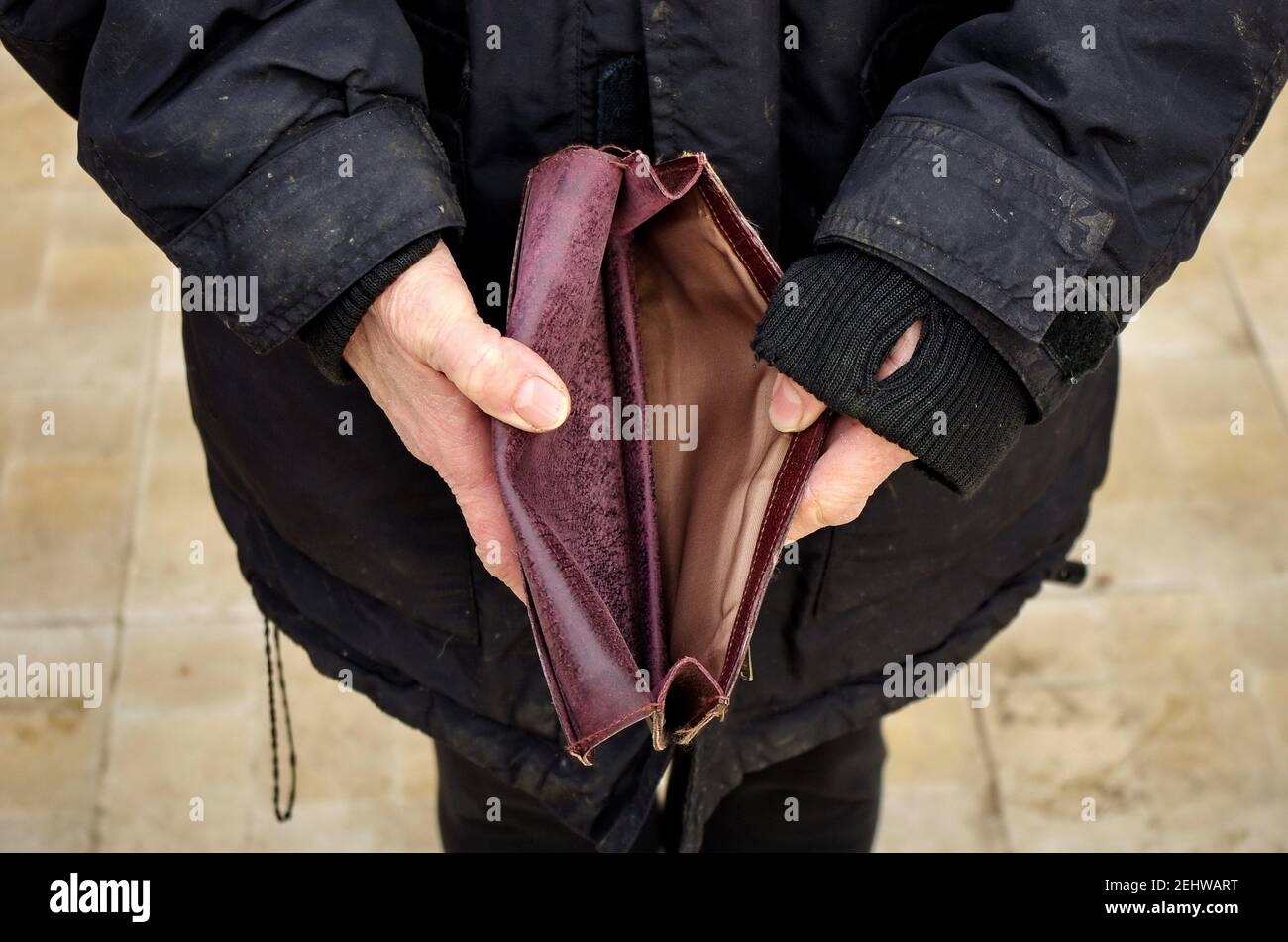 Eine ältere obdachlose arme Frau hält eine leere Brieftasche oder Geldbörse. Das Konzept der Armut im Ruhestand. Globale extreme Armut. Kein Geld hilft mir. Stockfoto