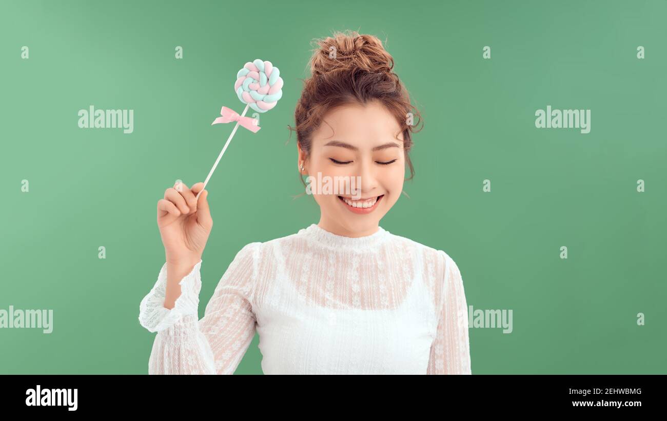 Nahaufnahme Porträt der schönen Mode fröhliche Frau essen süße Süßigkeiten Lolly Pop über grünen Hintergrund. Stockfoto Nahaufnahme Porträt der schönen Mode fröhliche Frau essen süße Süßigkeiten Lolly Pop über grünen Hintergrund. Stockfoto