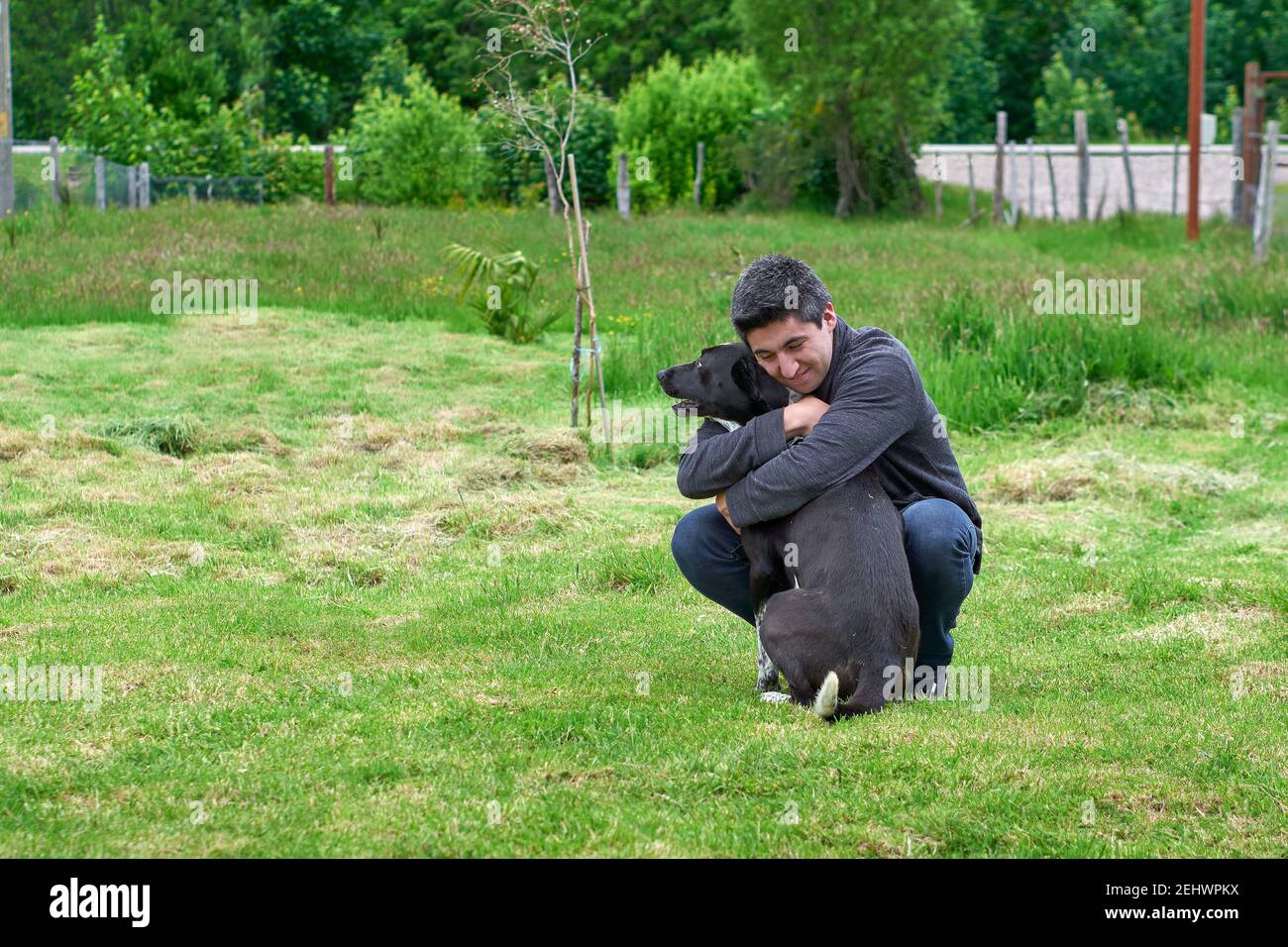 Junger Mann zeigt Zuneigung zu seinem Haustier, während er Zeit verbringt Im Freien Stockfoto