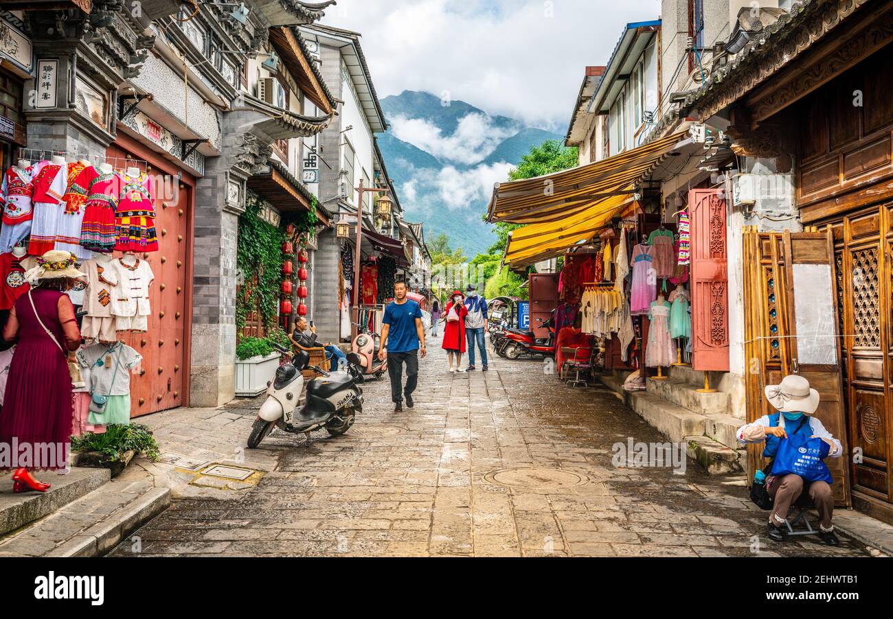 Dali China , 6 Oktober 2020 : Dali Altstadt Gasse mit alten Gebäuden Menschen und Cangshan Berg im Hintergrund in Dali Yunnan China Stockfoto