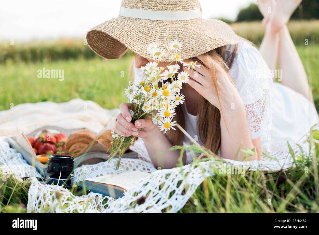 Mädchen in einem Feld mit Gänseblümchen, Sommer im Dorf.Junge lächelnde Frau im Freien entspannen und ein Picknick, sie liegt auf einer Decke auf dem Stockfoto