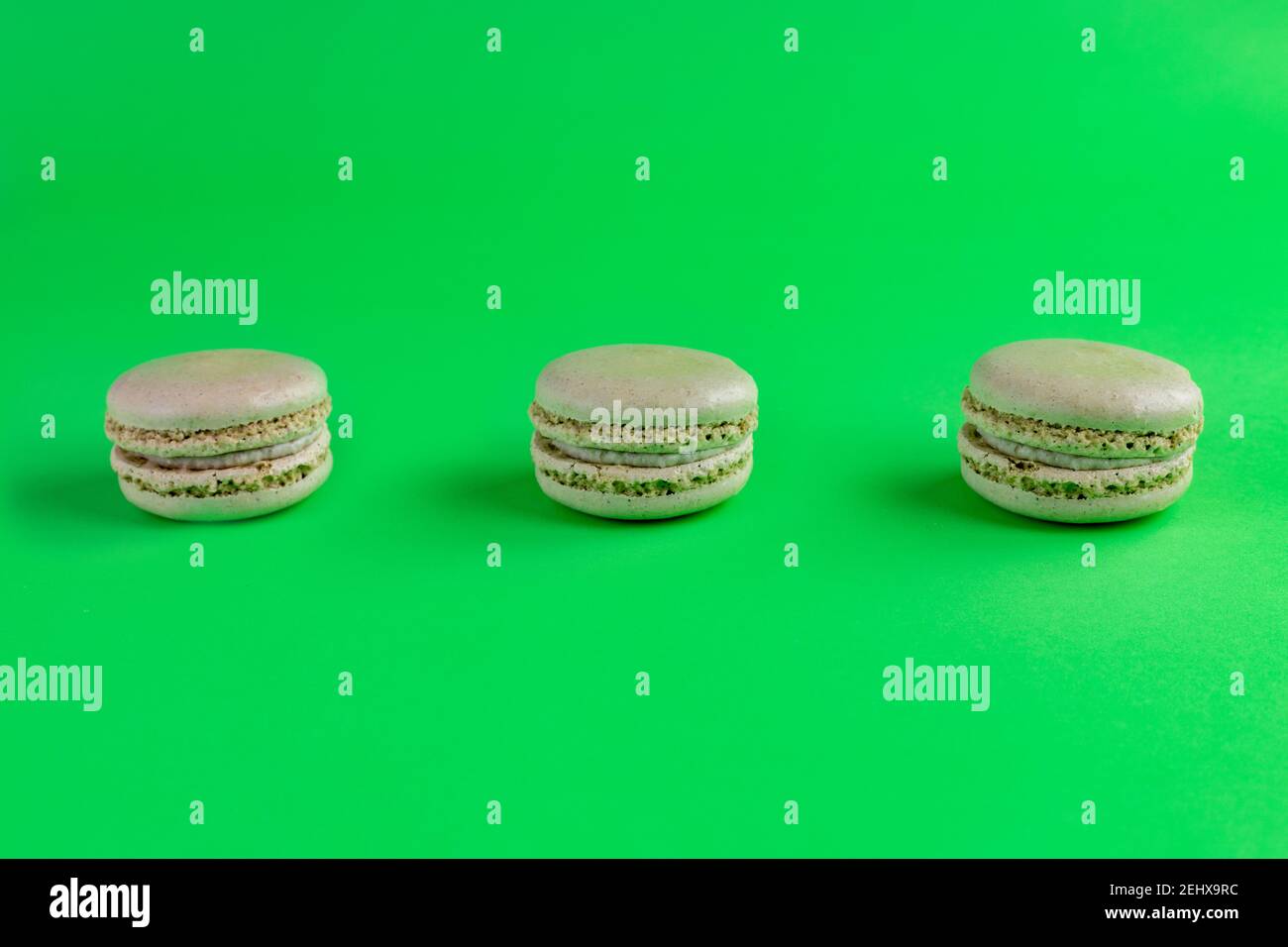 Grüne Macarons mit grünem Hintergrund aufgereiht Stockfoto