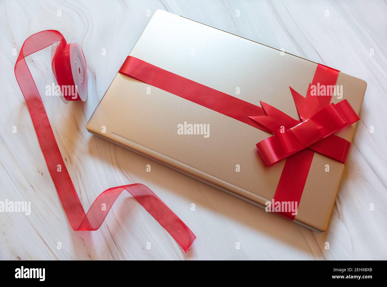 Laptop mit roter Geschenkschleife mit Hintergrund Ornamente gewickelt Stockfoto